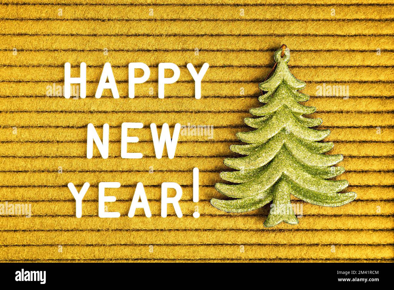 Felice anno nuovo , testo su cartoncino in feltro giallo con lettere bianche e abete giocattolo verde decorativo . Vista dall'alto, disposizione piatta Foto Stock