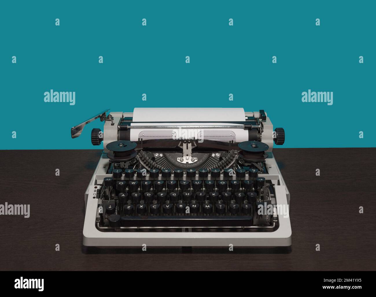 macchina da scrivere 70s senza coperchio superiore su tavolo di legno e sfondo blu Foto Stock