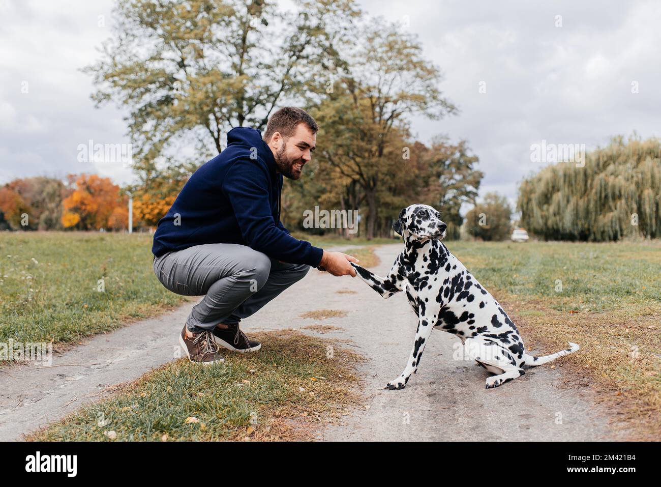 Bel giovane uomo con cane all'aperto. Uomo su erba verde con cane. Foto Stock