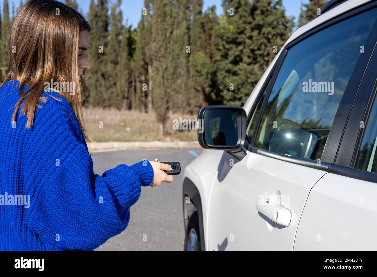 Le donne premono a mano i sistemi di allarme per auto con telecomando. Le donne premono a mano il pulsante sul telecomando per bloccare o sbloccare l'auto rossa, concetto di viaggio Foto Stock