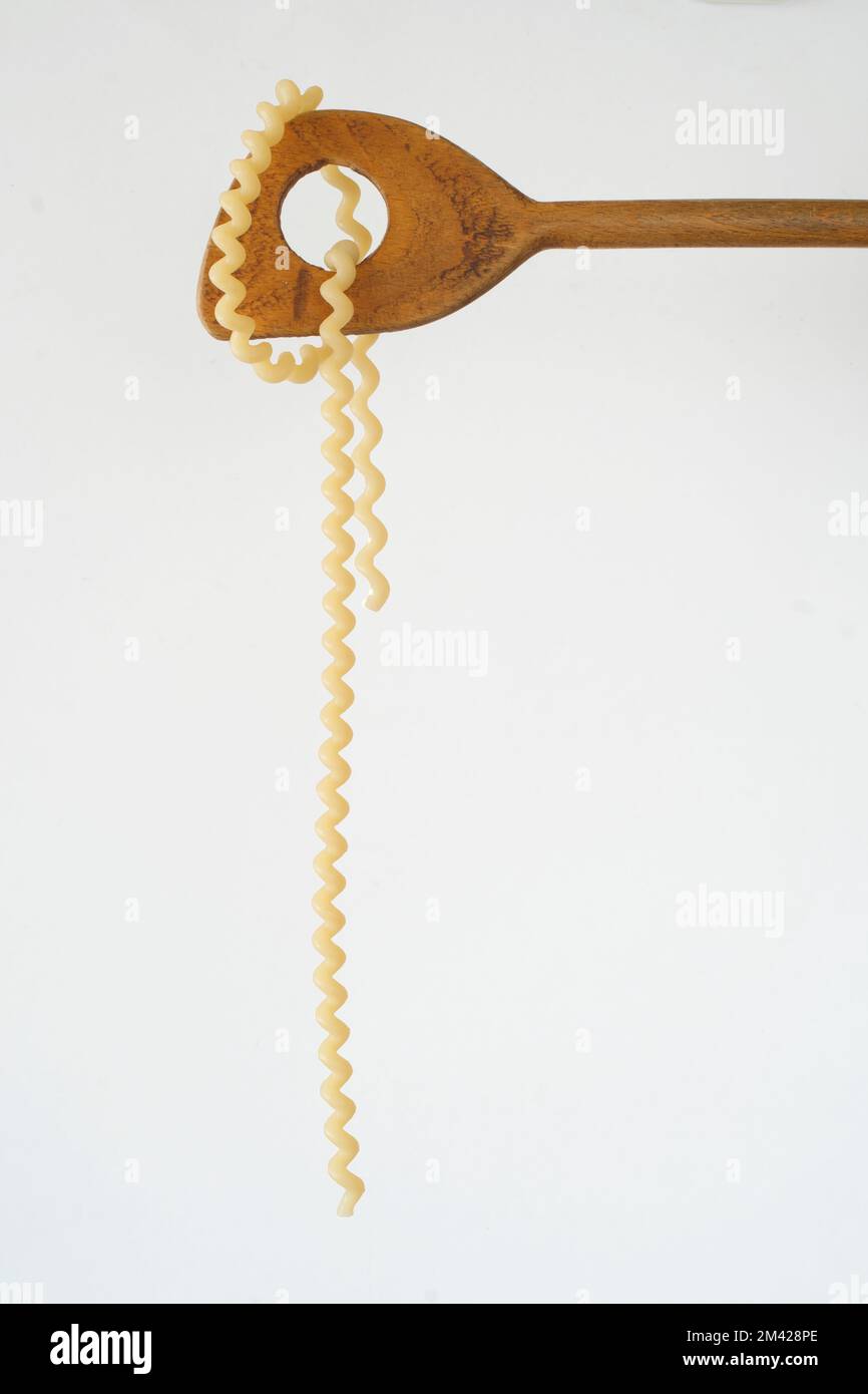 pasta italiana appesa ad un cucchiaio di legno, isolata su sfondo bianco, spazio copia libero Foto Stock