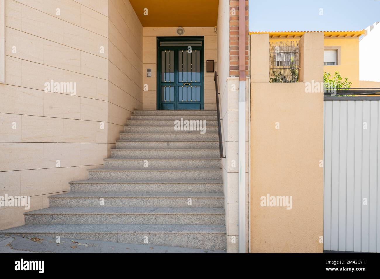 Portale d'ingresso ad un edificio residenziale con scale in granito, ringhiera in metallo nero e porta d'ingresso dipinta di verde Foto Stock