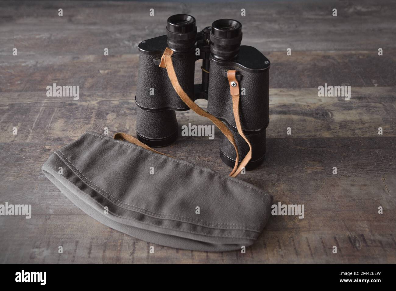 Vecchio binocolo militare in un berretto militare su un tavolo di legno. Foto Stock