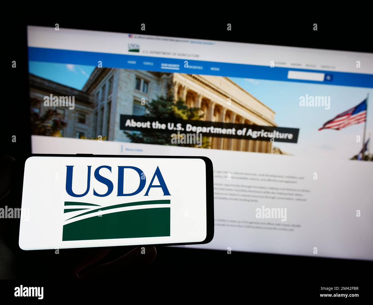 Persona che tiene lo smartphone con il logo del Ministero dell'Agricoltura degli Stati Uniti (USDA) sullo schermo davanti al sito Web. Messa a fuoco sul display del telefono. Foto Stock