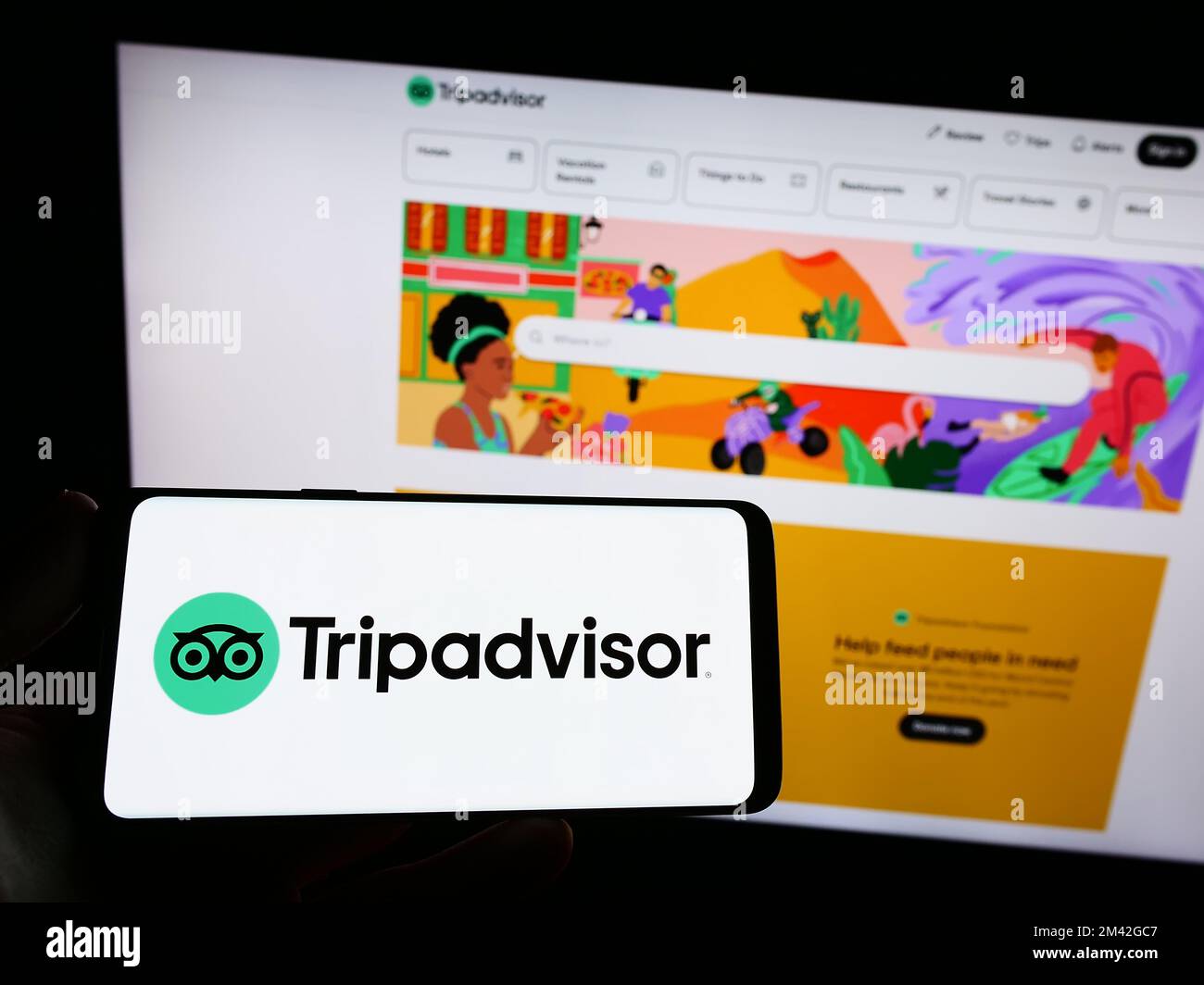 Persona che tiene uno smartphone con il logo della società di viaggi statunitense TripAdvisor Inc. Sullo schermo di fronte al sito Web. Messa a fuoco sul display del telefono. Foto Stock