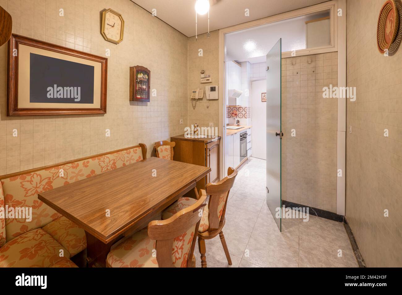 Ufficio di una cucina con una porta in vetro e un tavolo da pranzo pieghevole con sedie in legno e una panca a forma di L. Foto Stock