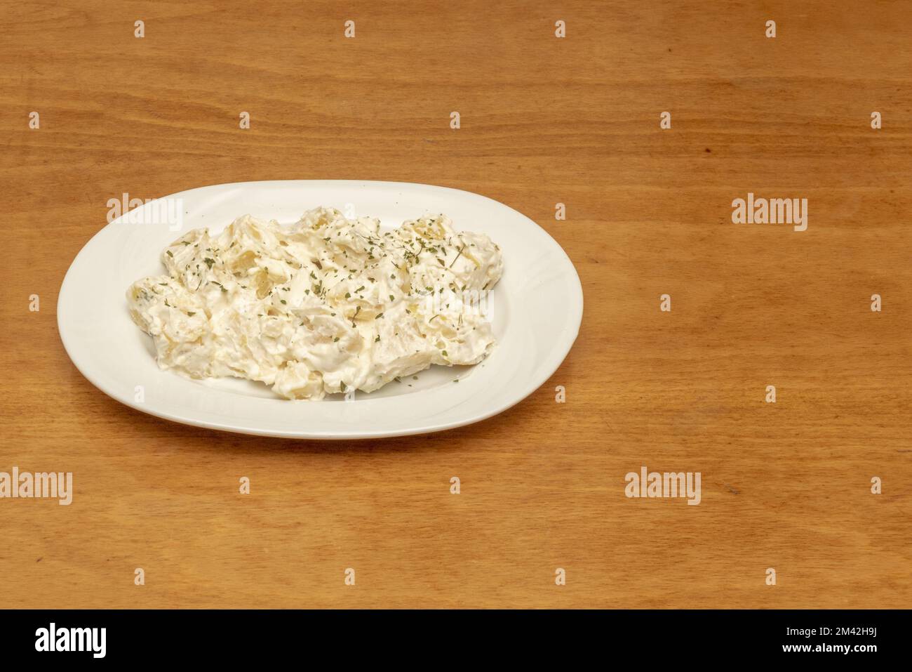 Una nota e popolare tapa spagnola di patate con salsa di alioli su un vassoio di porcellana bianca Foto Stock