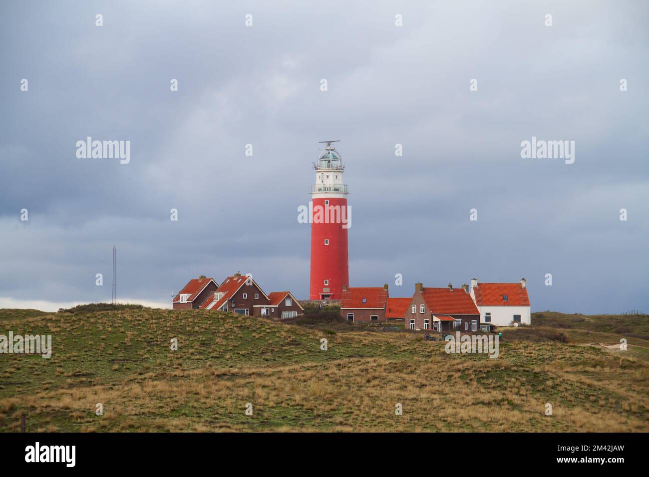 Il faro Eierland e alcune case bianche con tetti di tegole leggere nelle dune dell'isola olandese Texel nel mare di Wadden Foto Stock