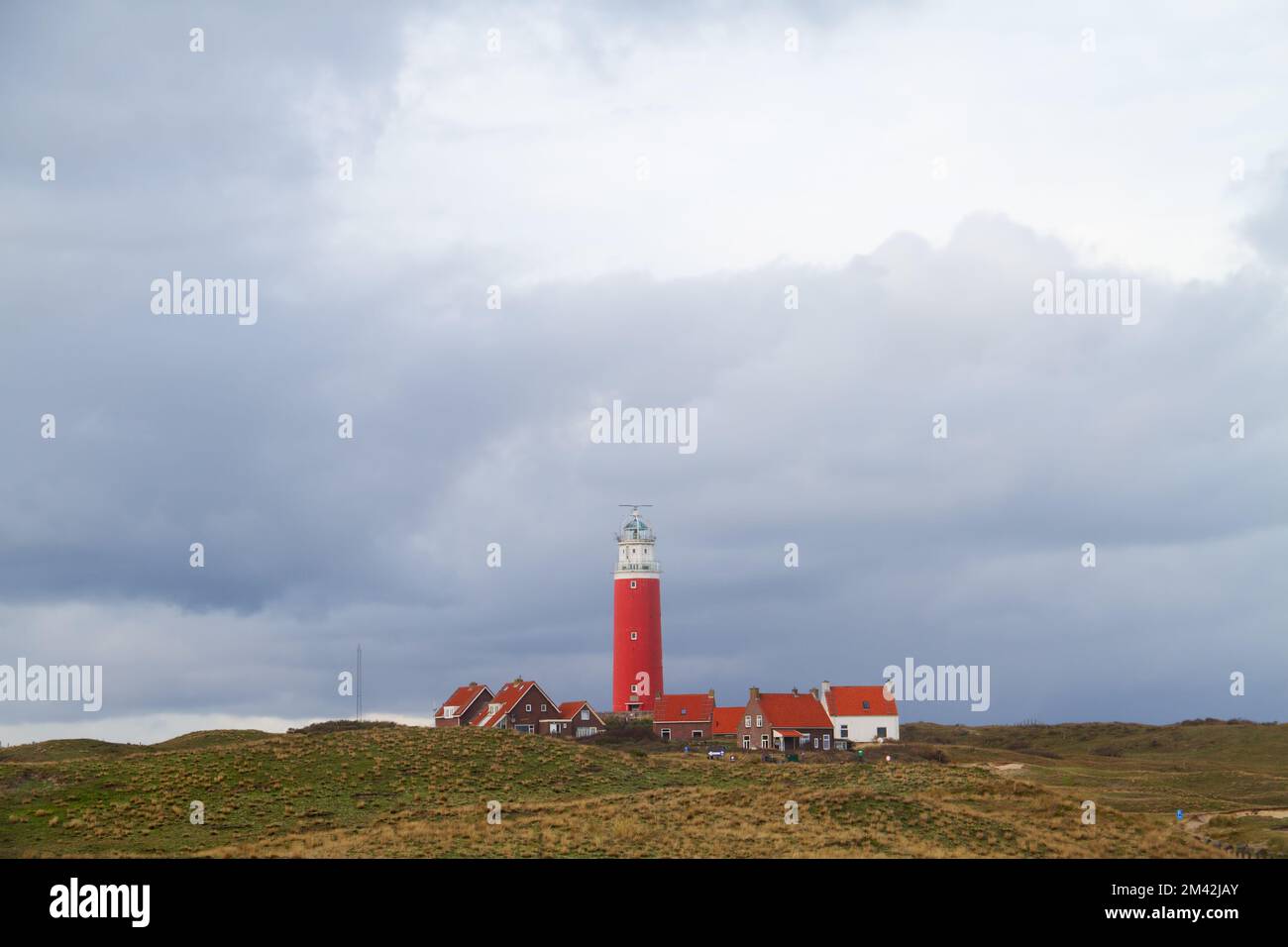 Il faro Eierland e alcune case bianche con tetti di tegole leggere nelle dune dell'isola olandese Texel nel mare di Wadden Foto Stock