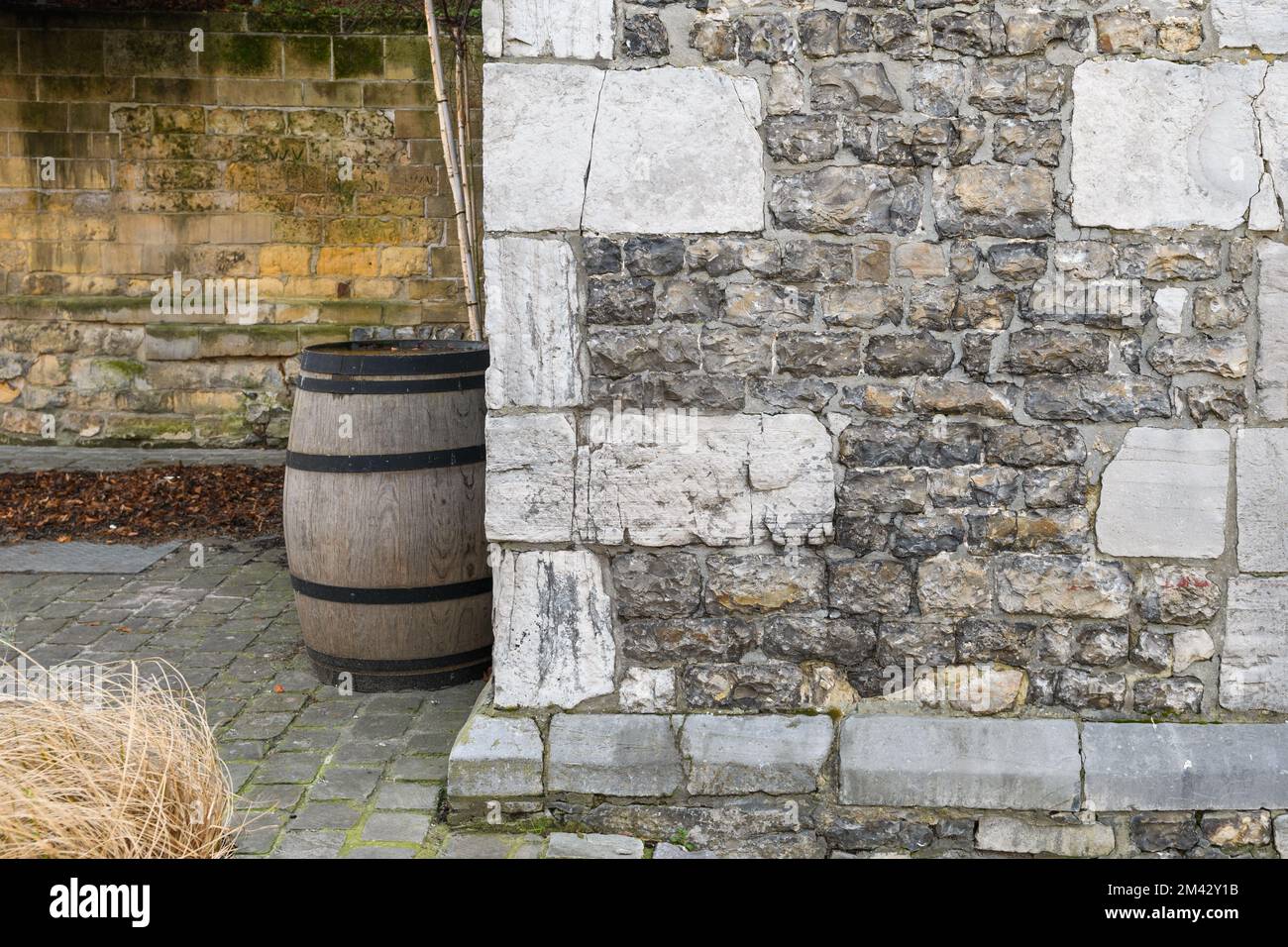 Un frammento di un vecchio cortile, un muro di pietra e un vecchio grande barile per il vino. background creativo Foto Stock