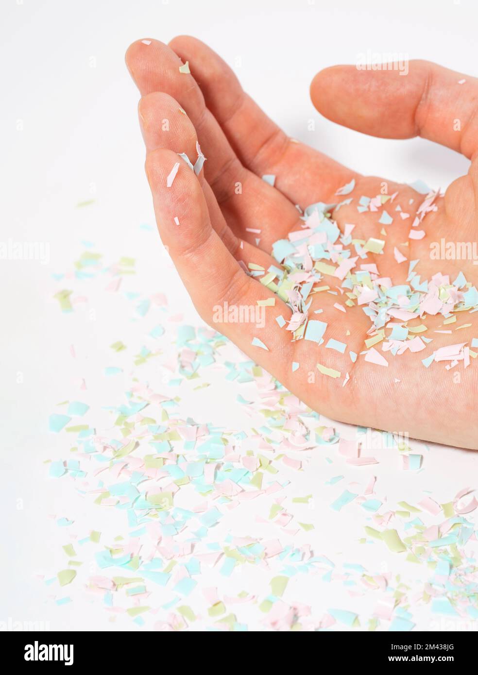 Un colpo di microplastica si trova sulla mano umana. Concetto di inquinamento idrico e riscaldamento globale. L'idea del danno ambientale. Sfondo bianco. Foto Stock