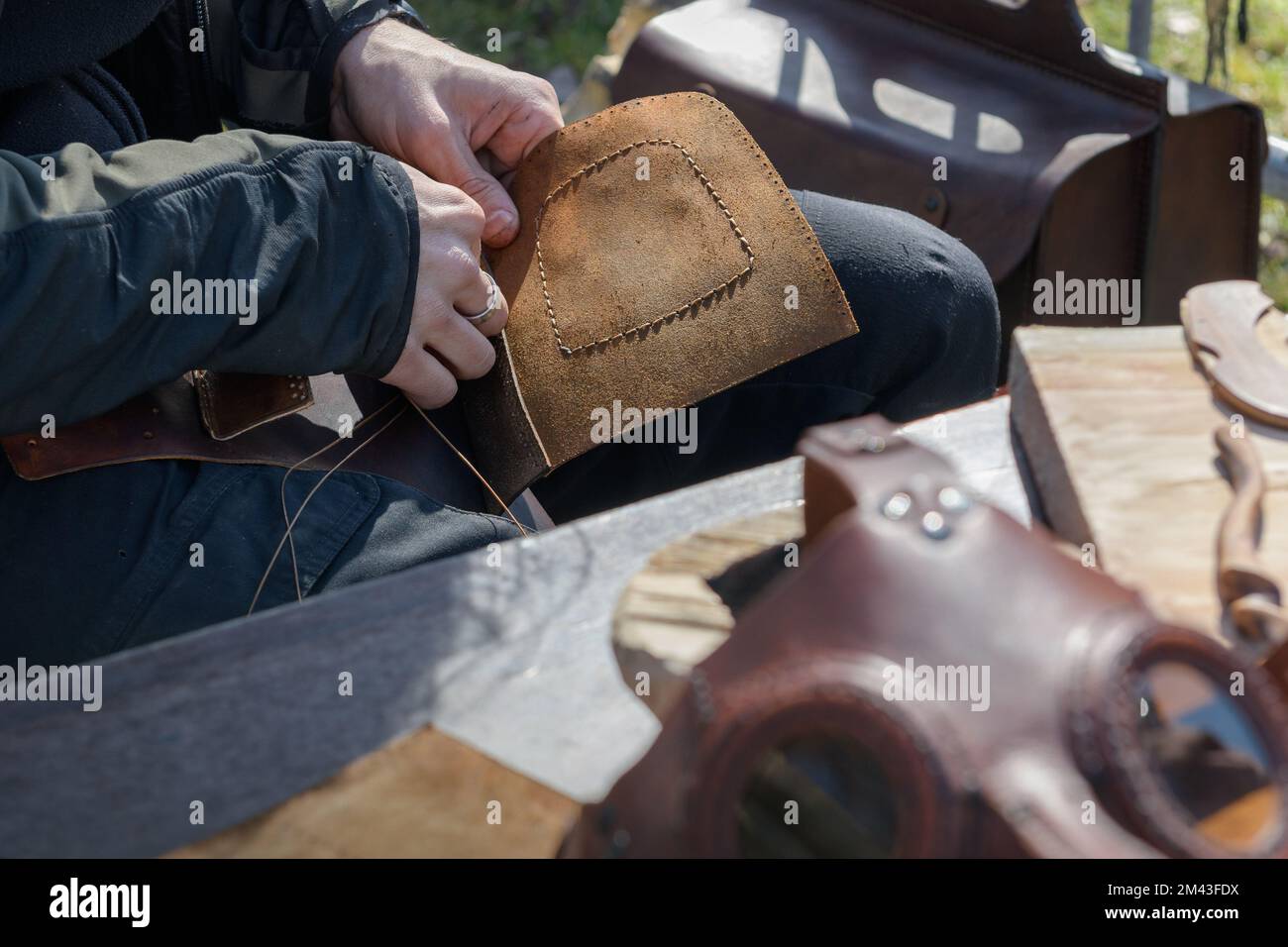 Cuciture in pelle a mano. Dettaglio di mani cucendo insieme un pezzo marrone di pelle con un ago Foto Stock