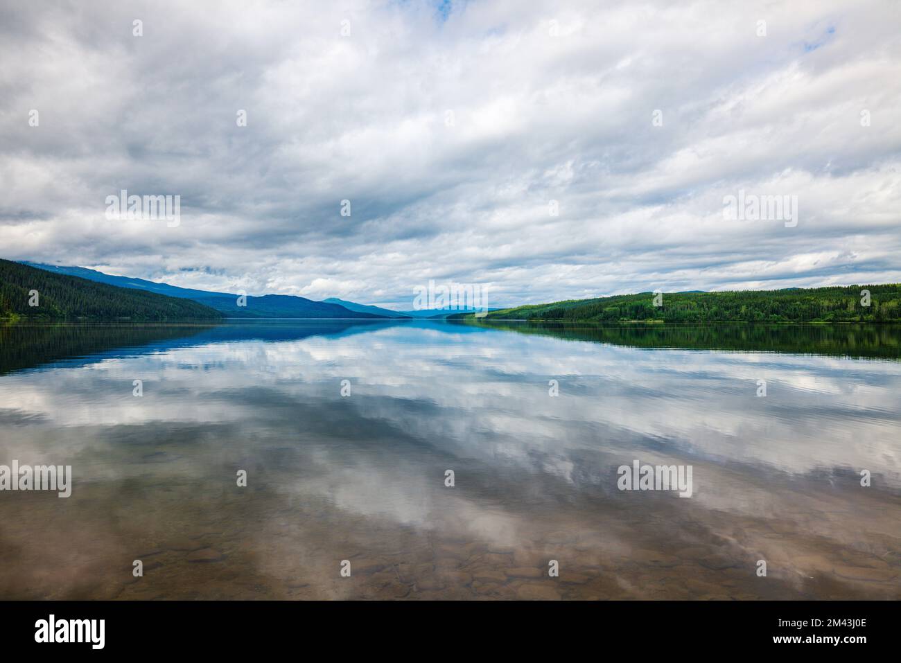 L'acqua ancora riflette le nuvole drammatiche; il lago Dease; la Columbia Britannica; il Canada Foto Stock