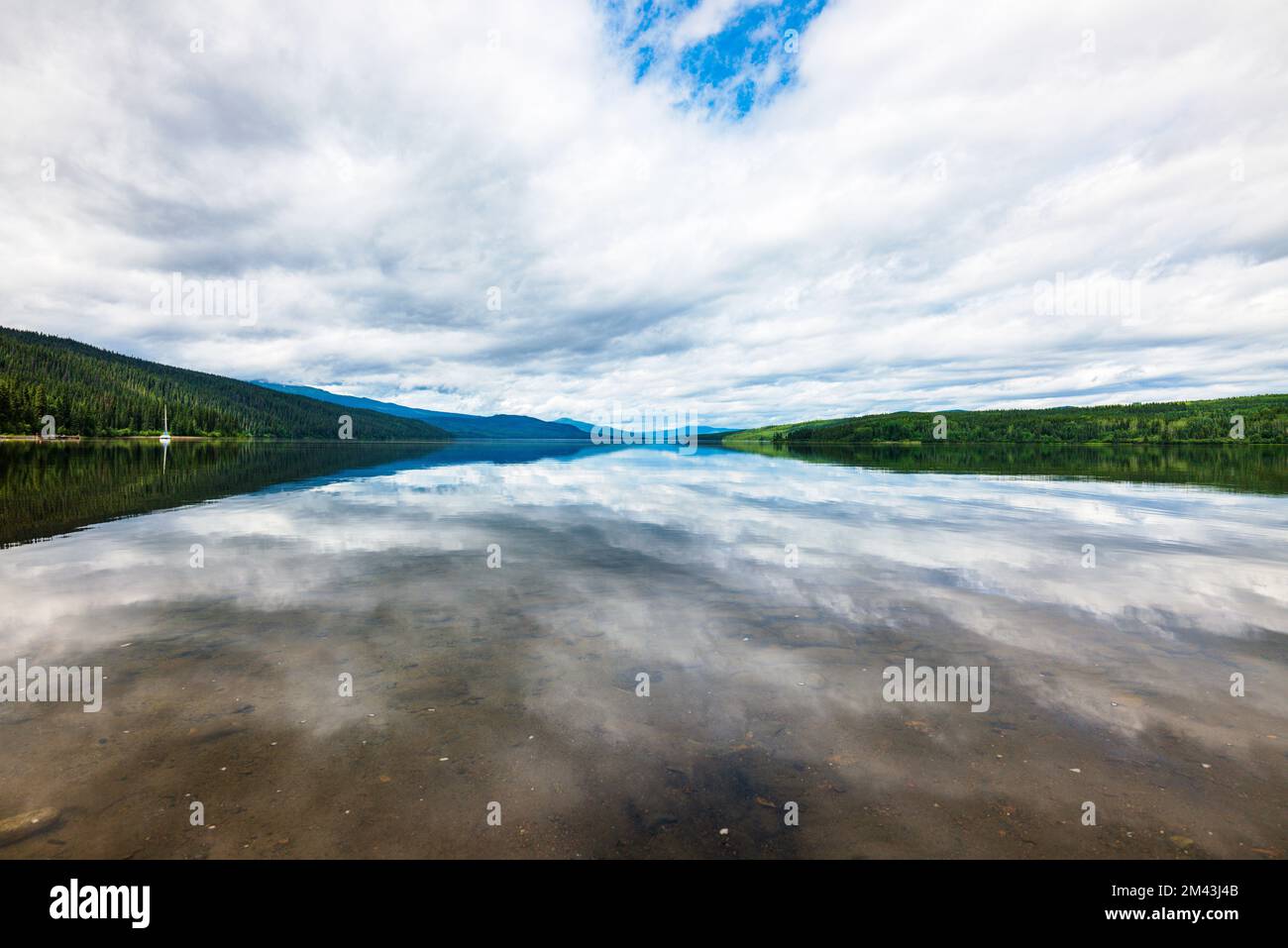 L'acqua ancora riflette le nuvole drammatiche; il lago Dease; la Columbia Britannica; il Canada Foto Stock