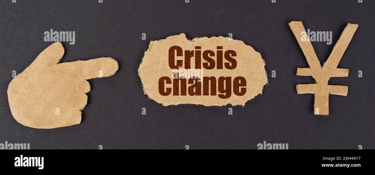 Economia e finanza. Su una superficie nera, una figura di una mano, un simbolo di yen e un cartone strappato con l'iscrizione - Crisis Change Foto Stock