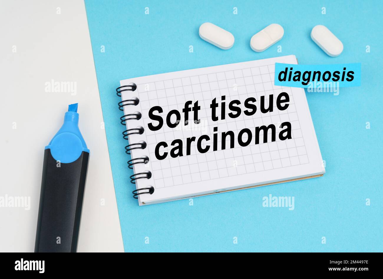 Medicina e concetto di salute. Su una superficie bianca e blu ci sono pillole, un marcatore e un notebook con l'iscrizione - carcinoma dei tessuti molli, un adesivo wi Foto Stock