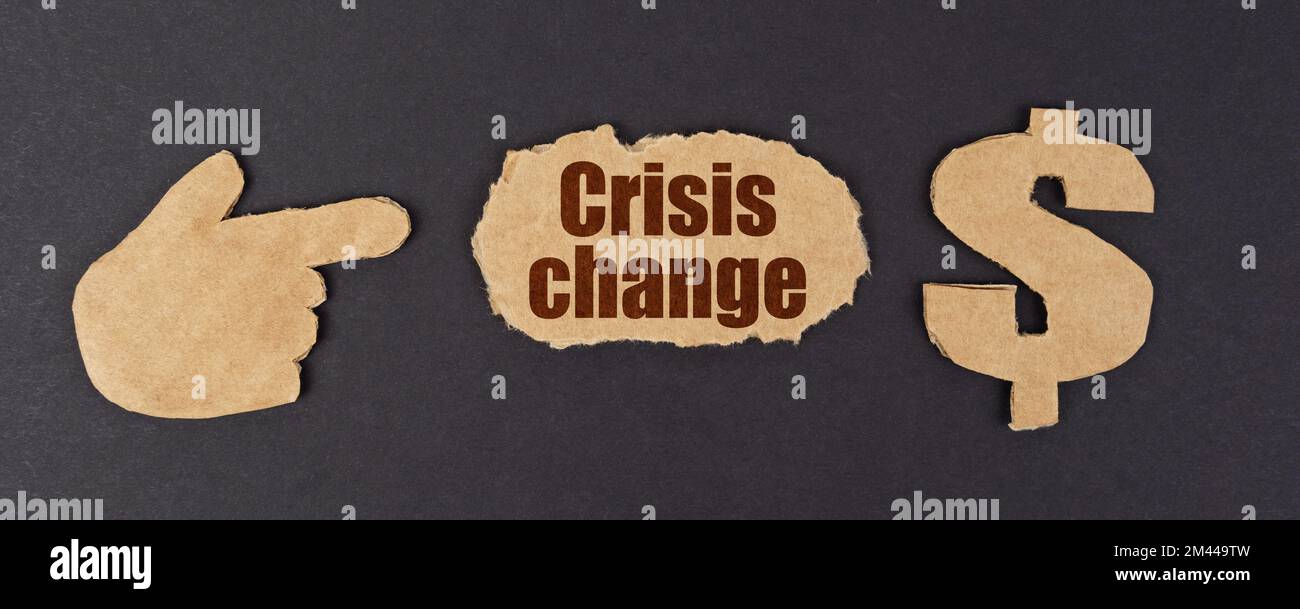 Economia e finanza. Su una superficie nera, una figura di una mano, un simbolo del dollaro e un cartone strappato con l'iscrizione - Crisis Change Foto Stock