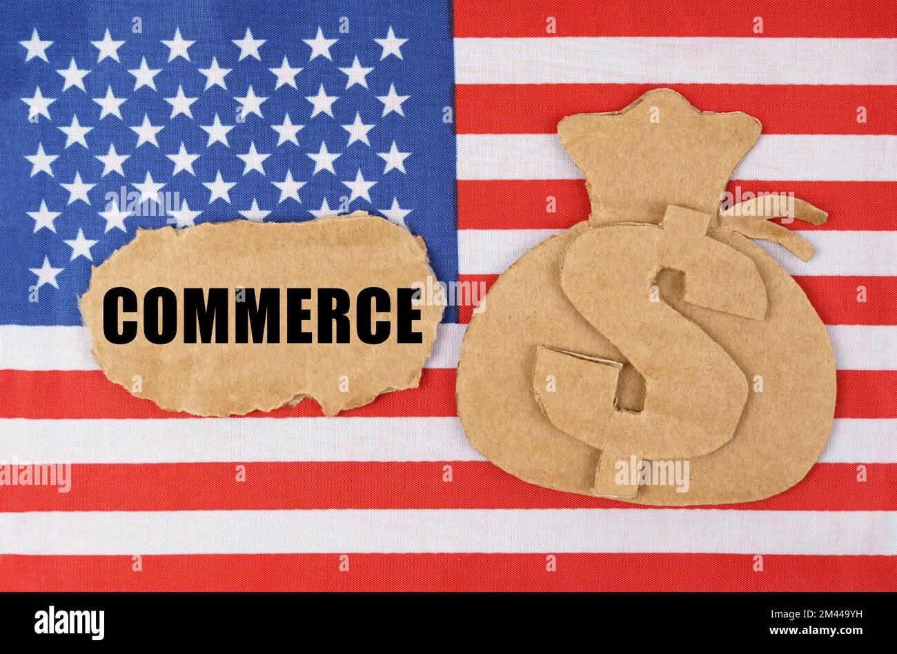 Il concetto di economia nazionale e di impresa. Sulla bandiera degli Stati Uniti, una figura di cartone di un sacchetto con il simbolo del dollaro e un cartone con l'iscrizione - Foto Stock