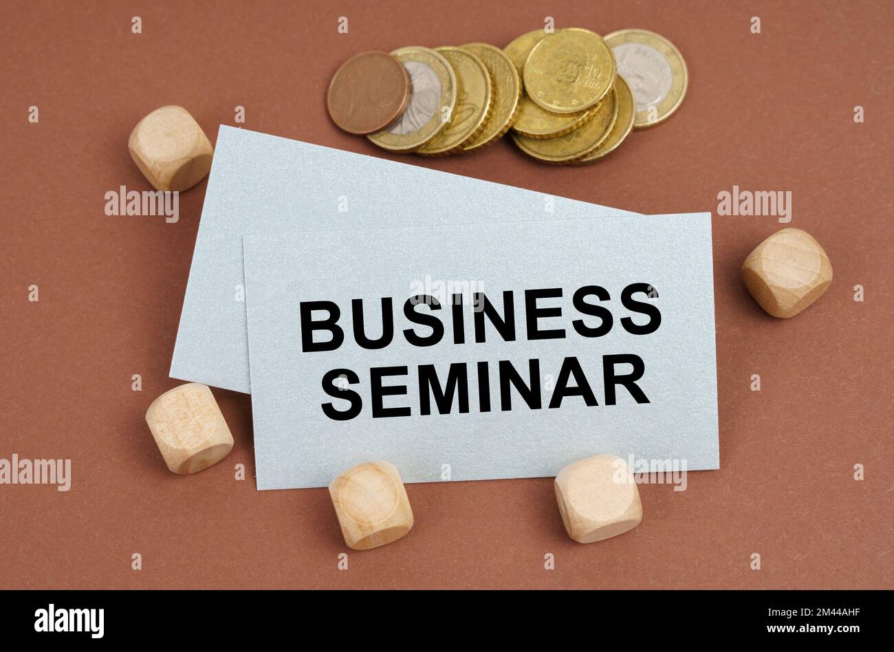 Concetto di business e finanza. Su una superficie marrone sono le monete, i cubi ed un biglietto da visita con l'iscrizione - SEMINARIO DI AFFARI Foto Stock
