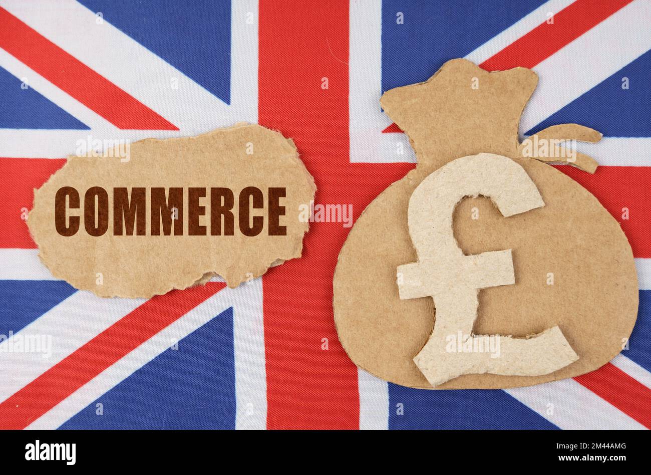 Il concetto di economia nazionale e di impresa. Sulla bandiera della Gran Bretagna si trova una figura di cartone di una borsa con un simbolo di denaro e un cartone con t Foto Stock