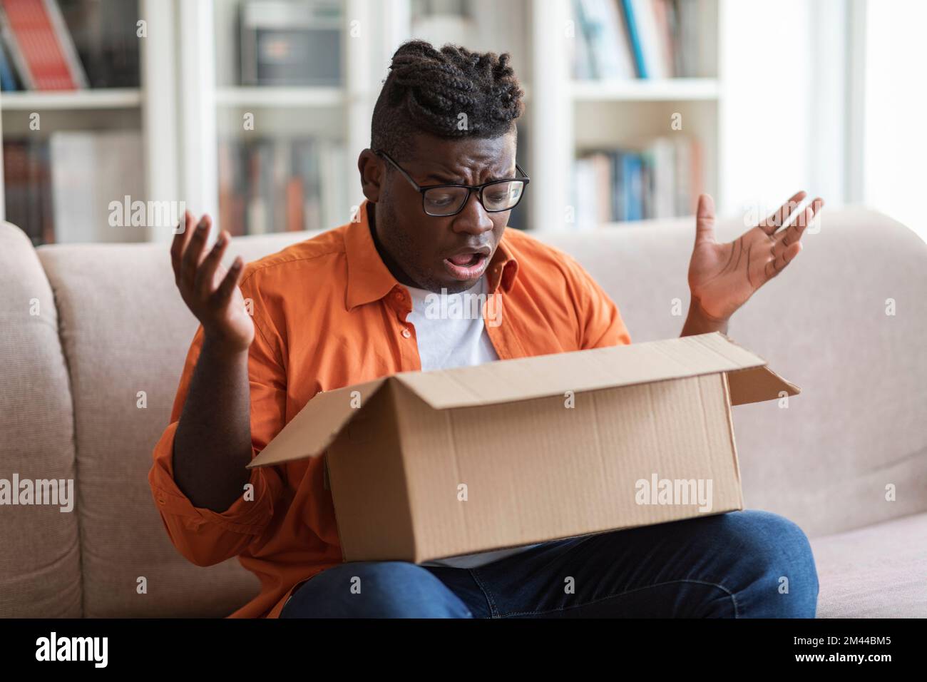 Scioccato afro americano giovane ragazzo cliente di apertura pacco Foto Stock
