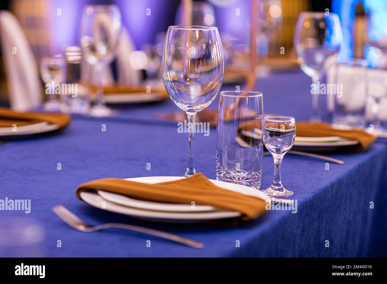 Natale festivo, matrimonio, tavolo di compleanno impostazione con tovaglia  blu, tovagliolo arancione posate, piatti bianchi, bicchieri per il vino,  acqua e forte alcova Foto stock - Alamy