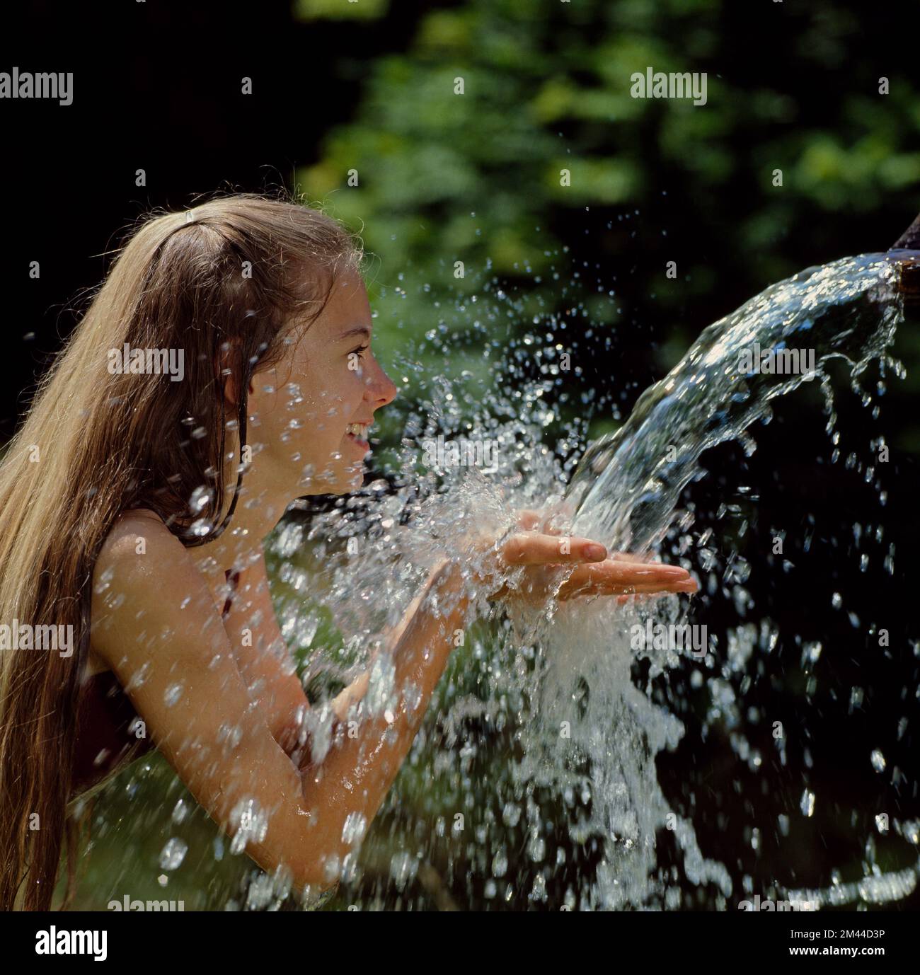 Junge Frau trinkt aus der quelle | giovane donna che beve acqua fresca da una sorgente Foto Stock