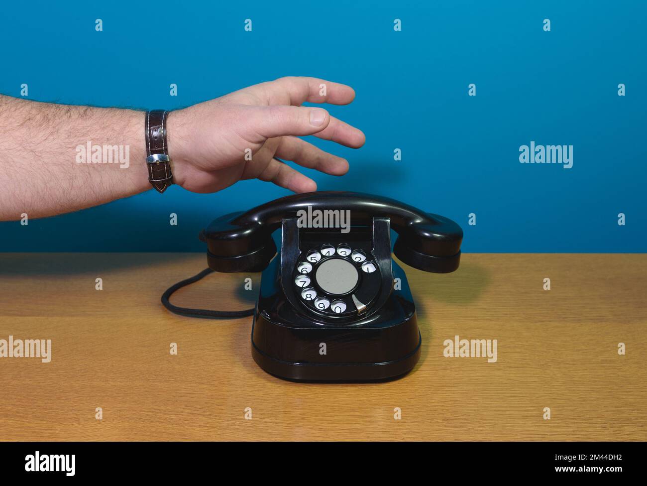 Chiamata di emergenza. La mano raggiunge il vecchio telefono. Vecchio telefono su un tavolo di legno. Spazio di copia Foto Stock