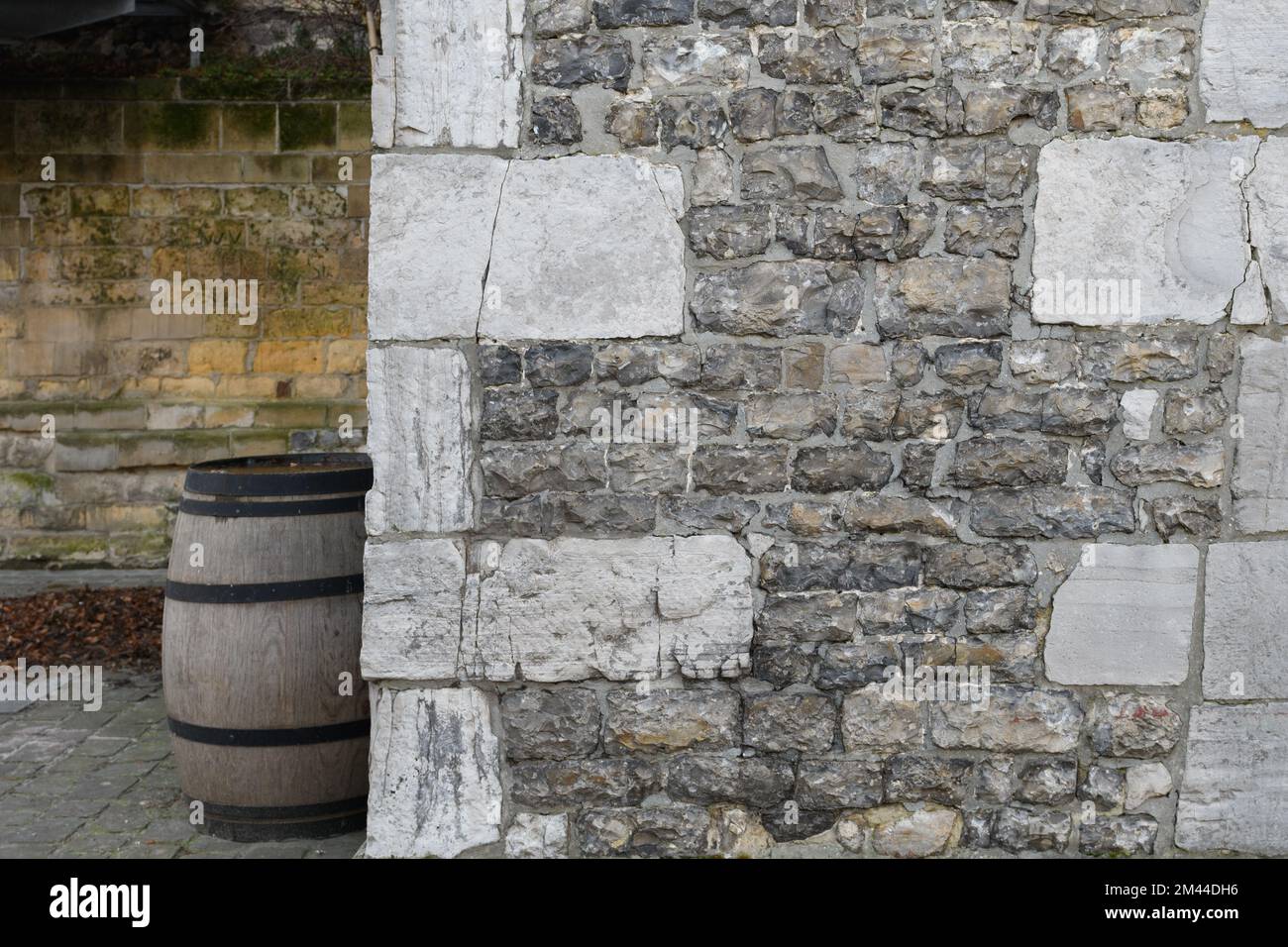 Frammento di un vecchio cortile, un muro di pietra e un vecchio grande barile per il vino. background creativo Foto Stock