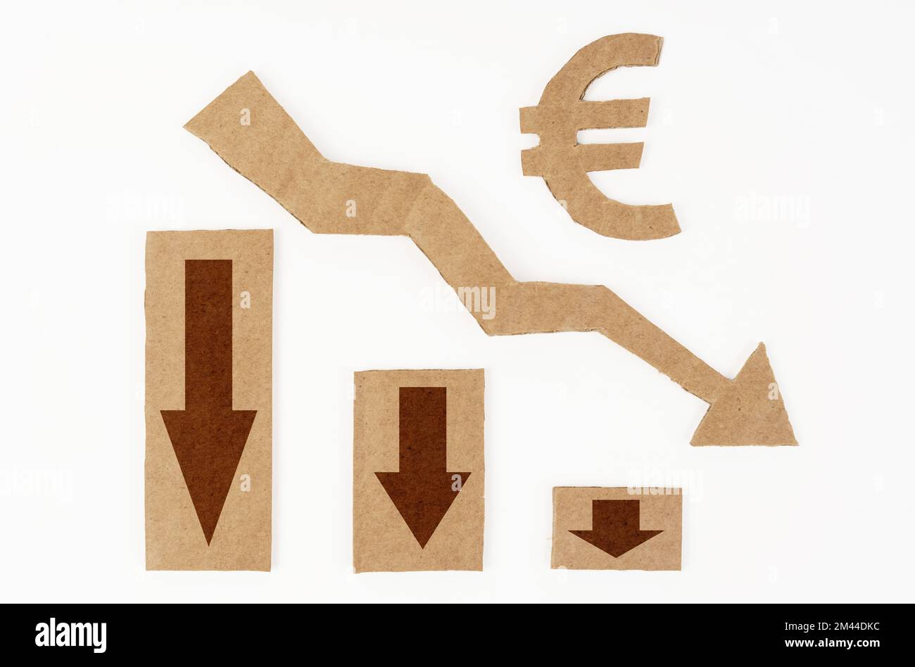 Il concetto di crisi economica. Su una superficie bianca, un grafico con le frecce verso il basso e un simbolo dell'euro. Simbolo, freccia e grafico sono realizzati in cartone Foto Stock