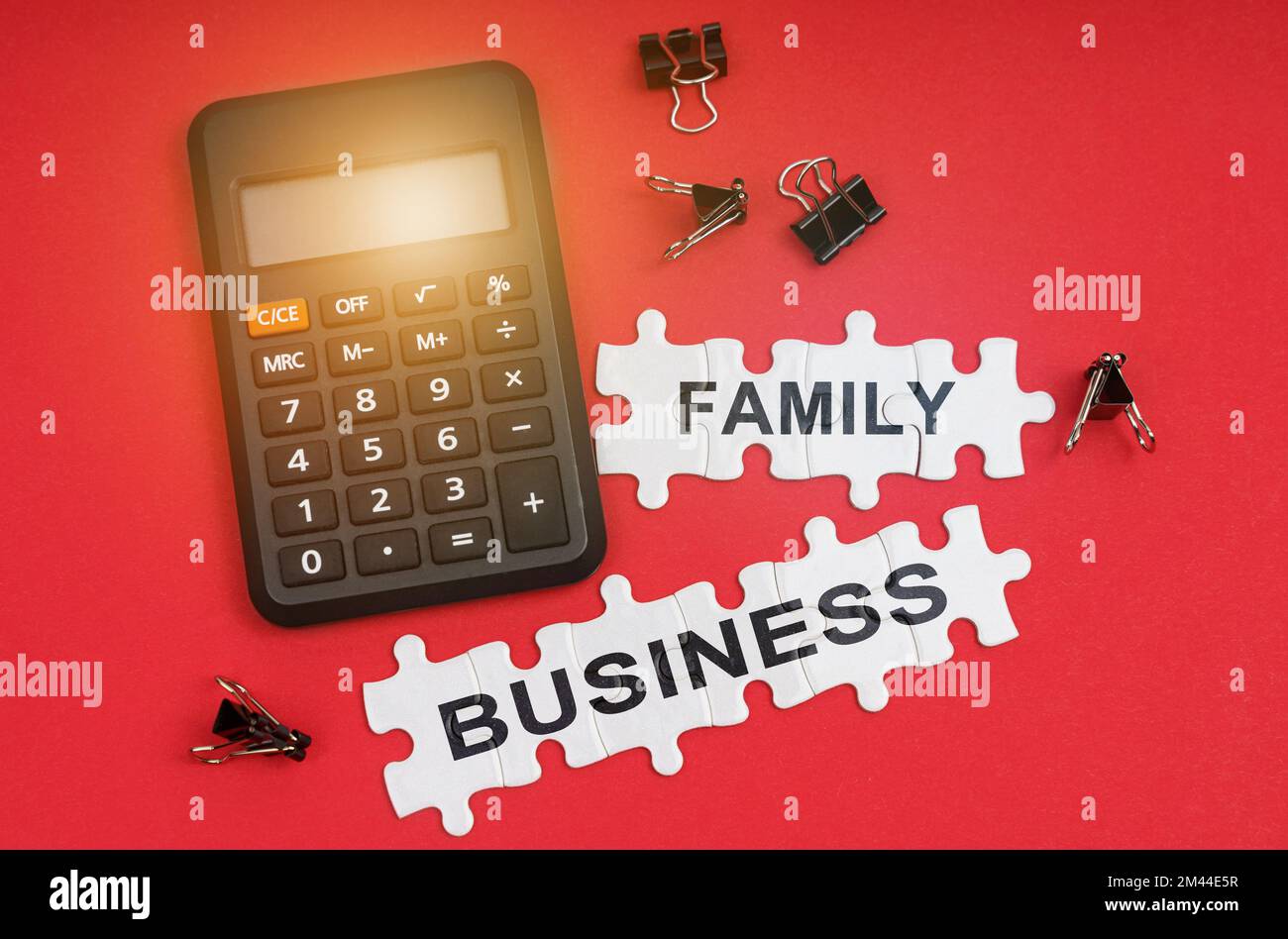 Concetto di finanza ed economia. Sulla superficie rossa ci sono una calcolatrice, morsetti e puzzle con l'iscrizione - BUSINESS DI FAMIGLIA Foto Stock