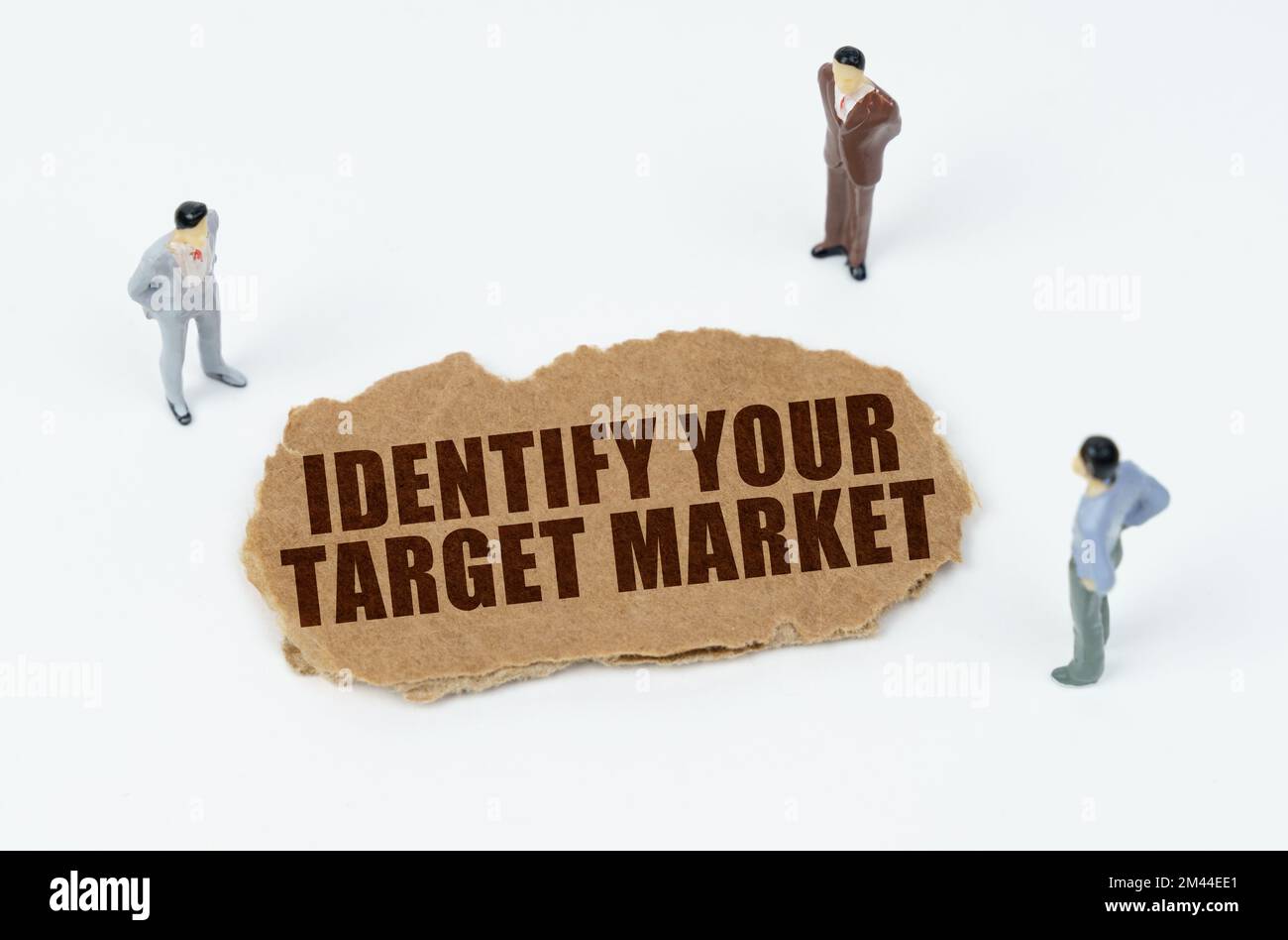 Economia e business concept. Su uno sfondo bianco, figure di uomini d'affari e cartone strappato con l'iscrizione - IDENTIFICARE IL VOSTRO MERCATO DI DESTINAZIONE Foto Stock