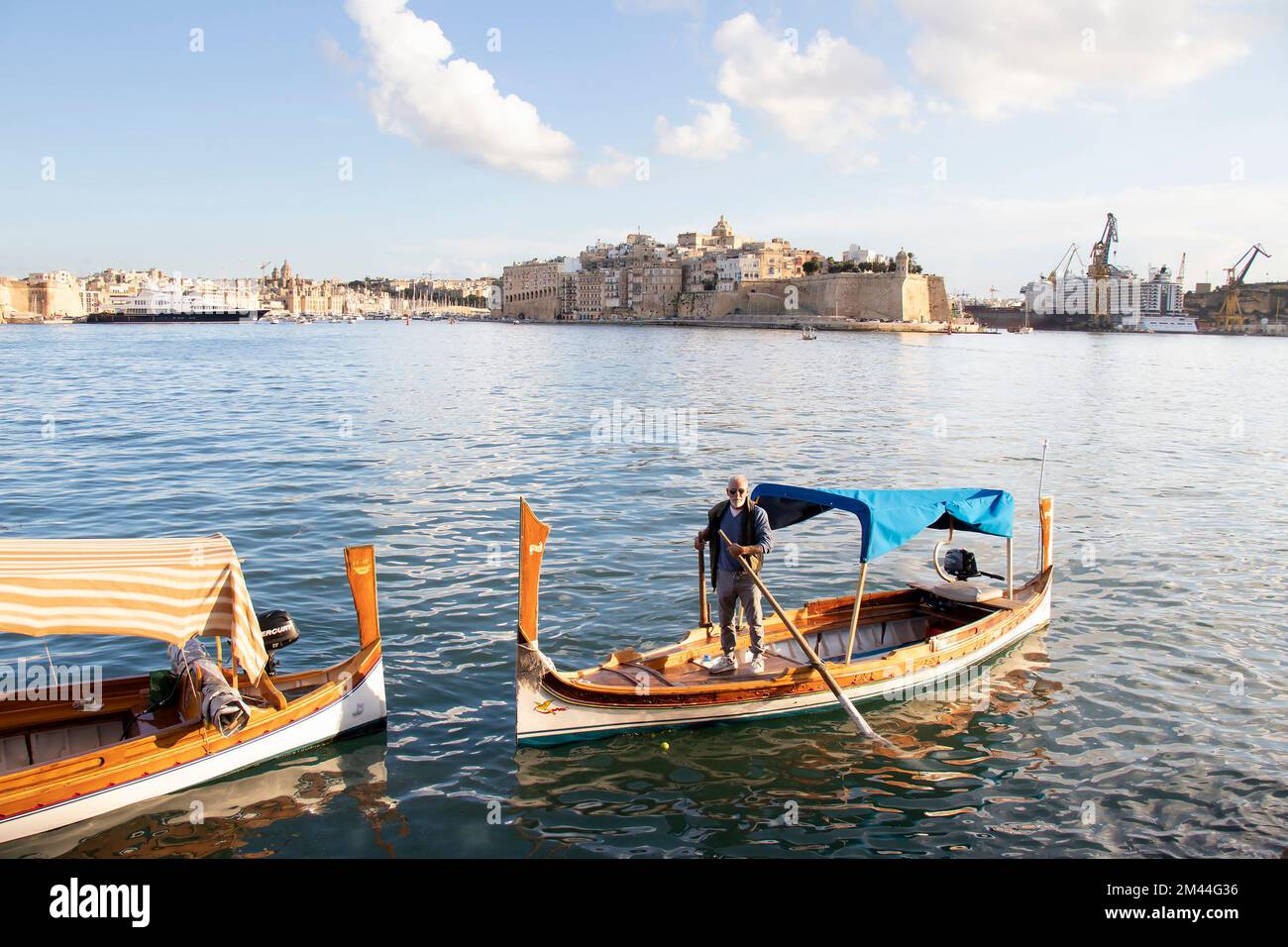 Valletta, Malta - 13 novembre 2022: Stazione dei taxi d'acqua Lascaris con il tradizionale battello di taxi d'acqua maltese, Dghajsa, e il suo autista, a la Valletta landin Foto Stock