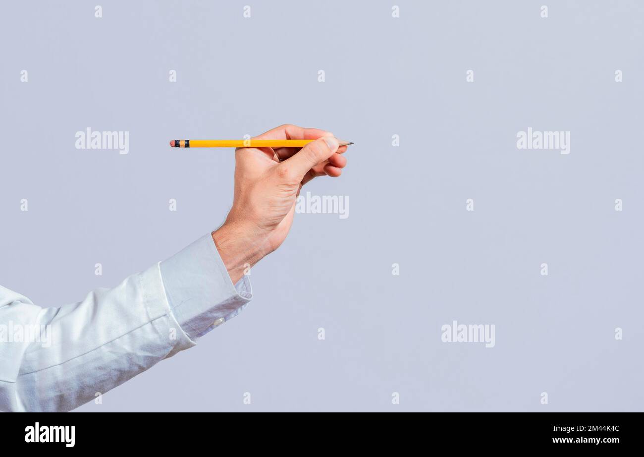 Mano maschile che tiene una matita su un bianco. Man dita tenendo una matita con spazio vuoto. Mani della persona che tiene una matita su uno spazio per il testo, mano con un Foto Stock