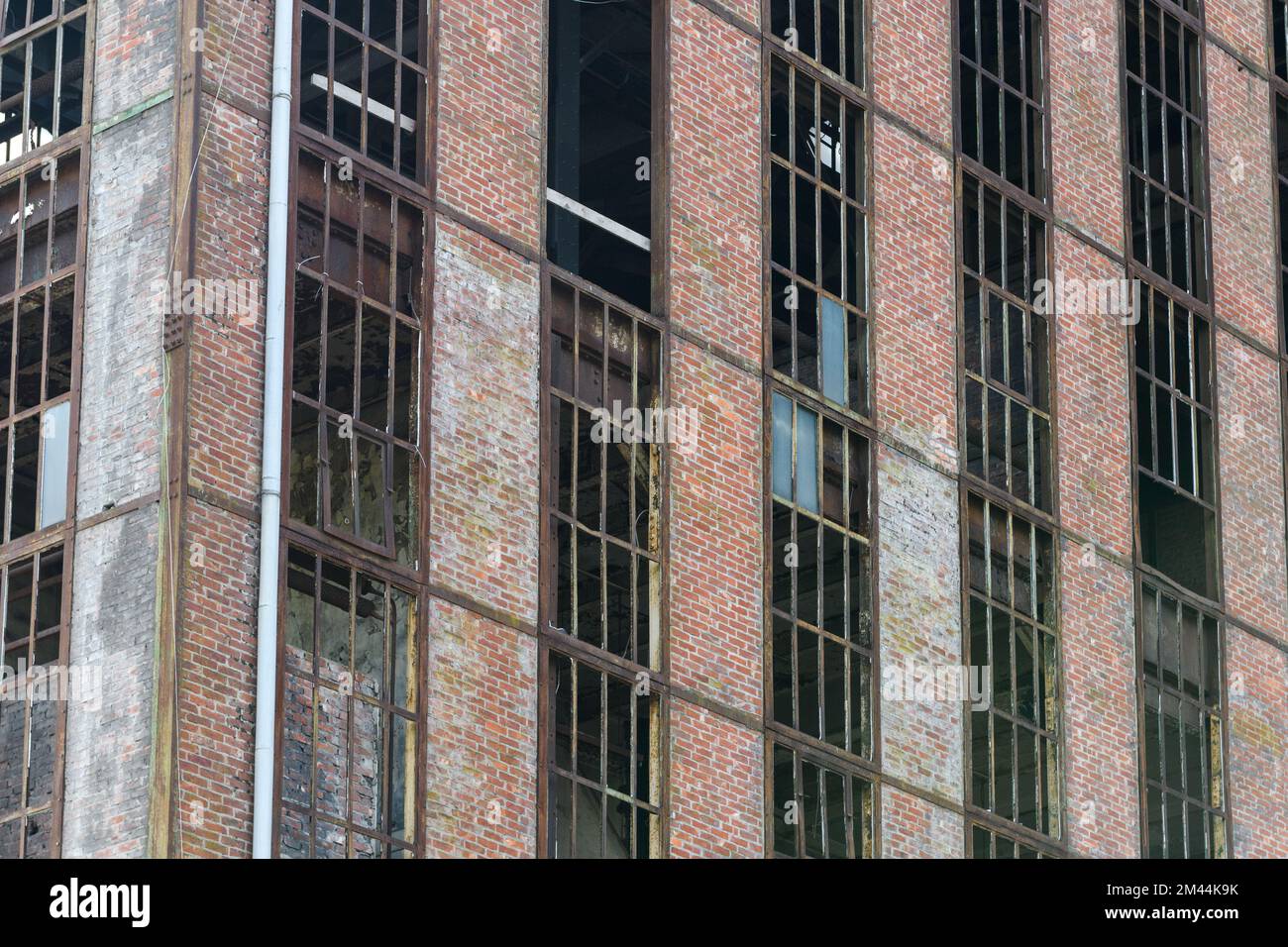 Facciata di una vecchia fabbrica abbandonata. Finestre arrugginite senza vetro. Foto Stock
