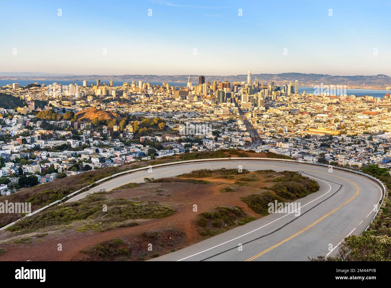 Vista rialzata del centro di San Francisco al tramonto in autunno. Una strada tortuosa è visibile in primo piano. Foto Stock