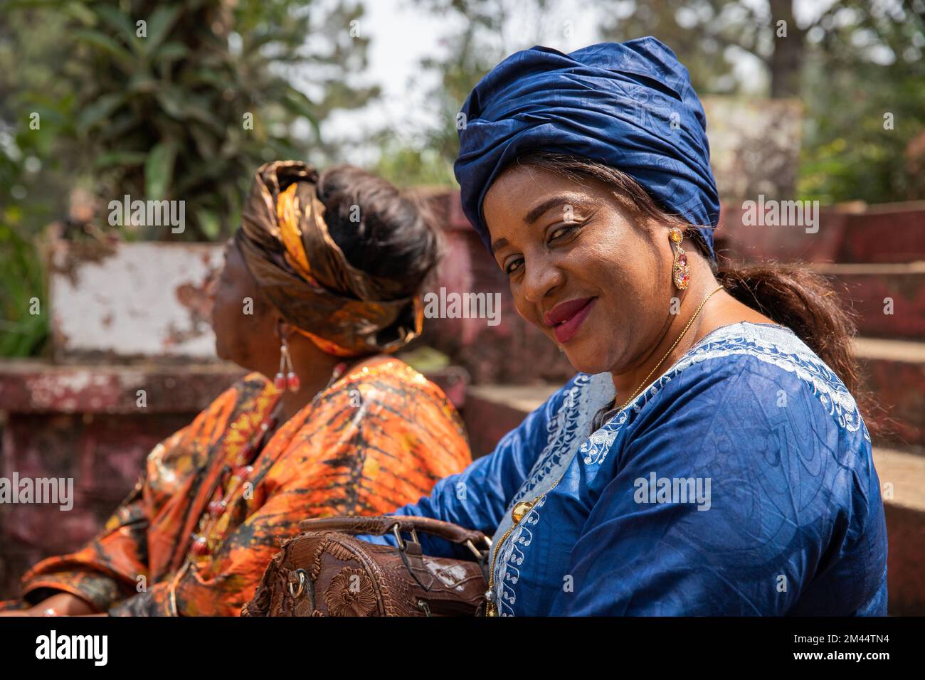 Ritratto di una donna africana sorridente vestita con abiti tradizionali accanto ad un amico Foto Stock