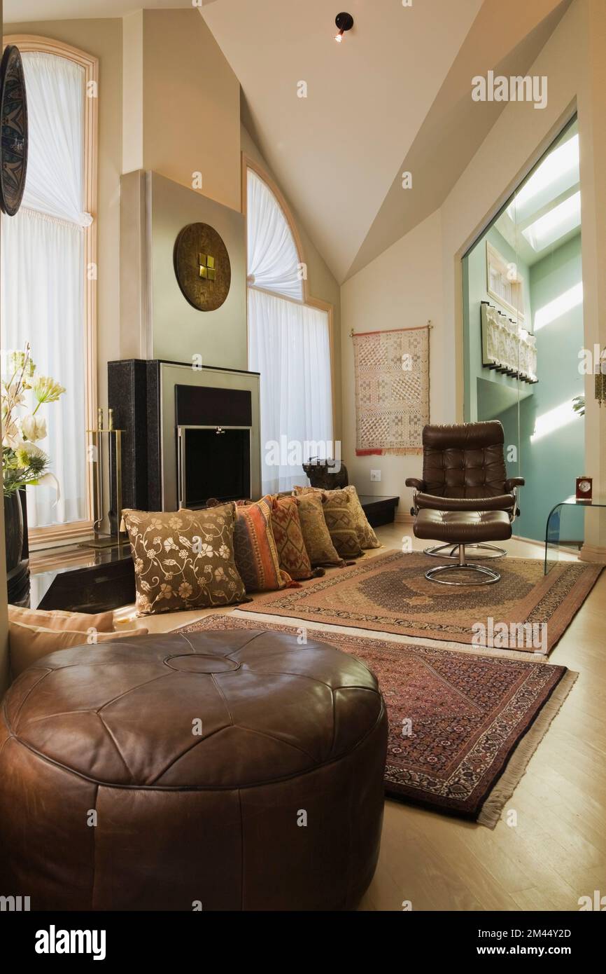 Cuscino in pelle marrone e poltrona girevole con poggiapiedi in stile marocchino, camera da letto principale decorata all'interno di una lussuosa casa contemporanea. Foto Stock