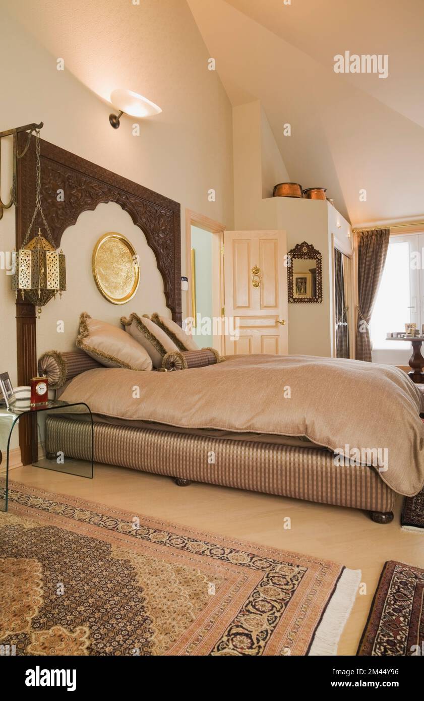 Letto queen size con testata in legno in stile marocchino decorata camera da letto principale all'interno di una casa contemporanea, Quebec, Canada. Questa immagine è una release della proprietà Foto Stock