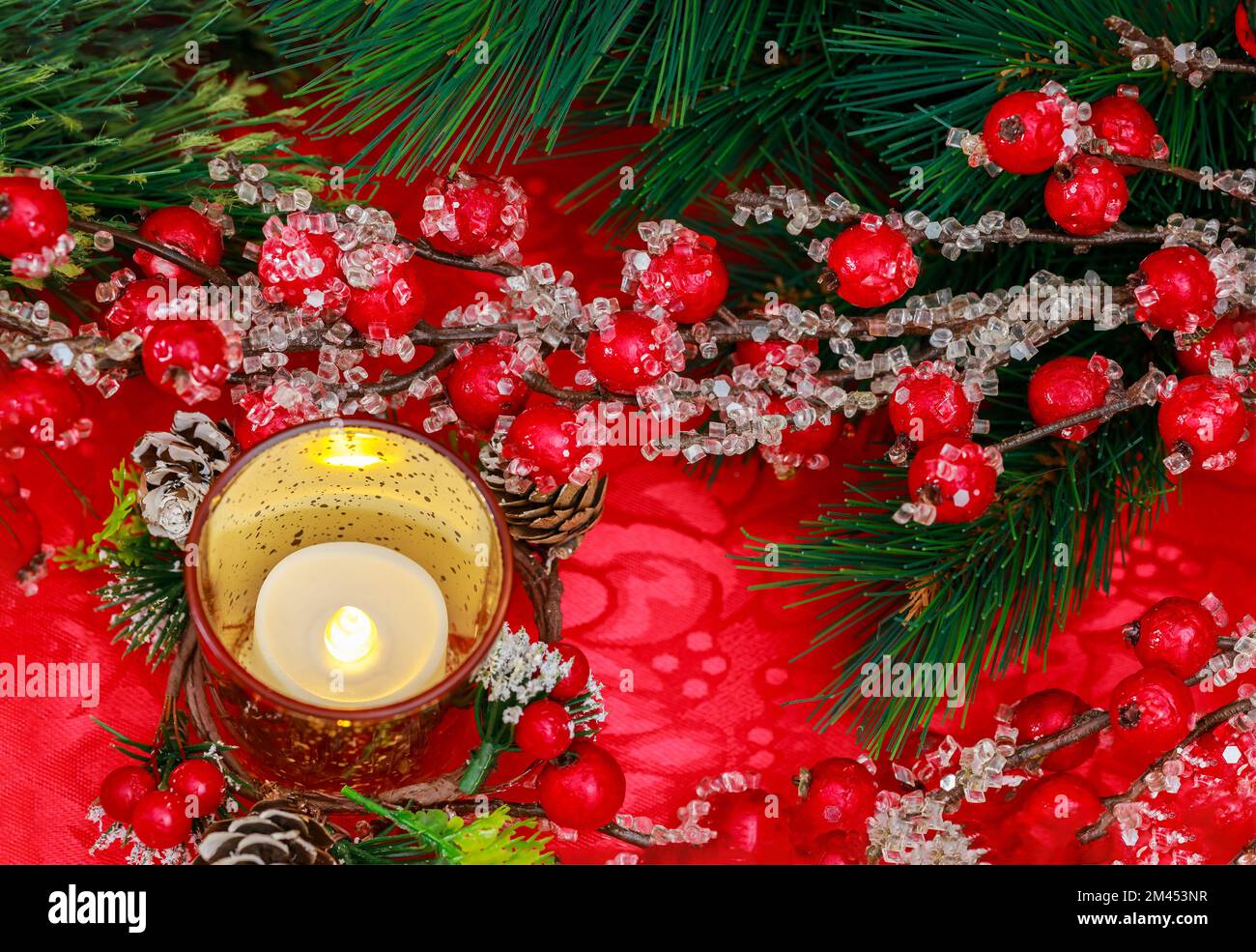 Un'atmosfera di festivita' e' creata a Natale da bacche rosse e candele bruciate. Foto Stock