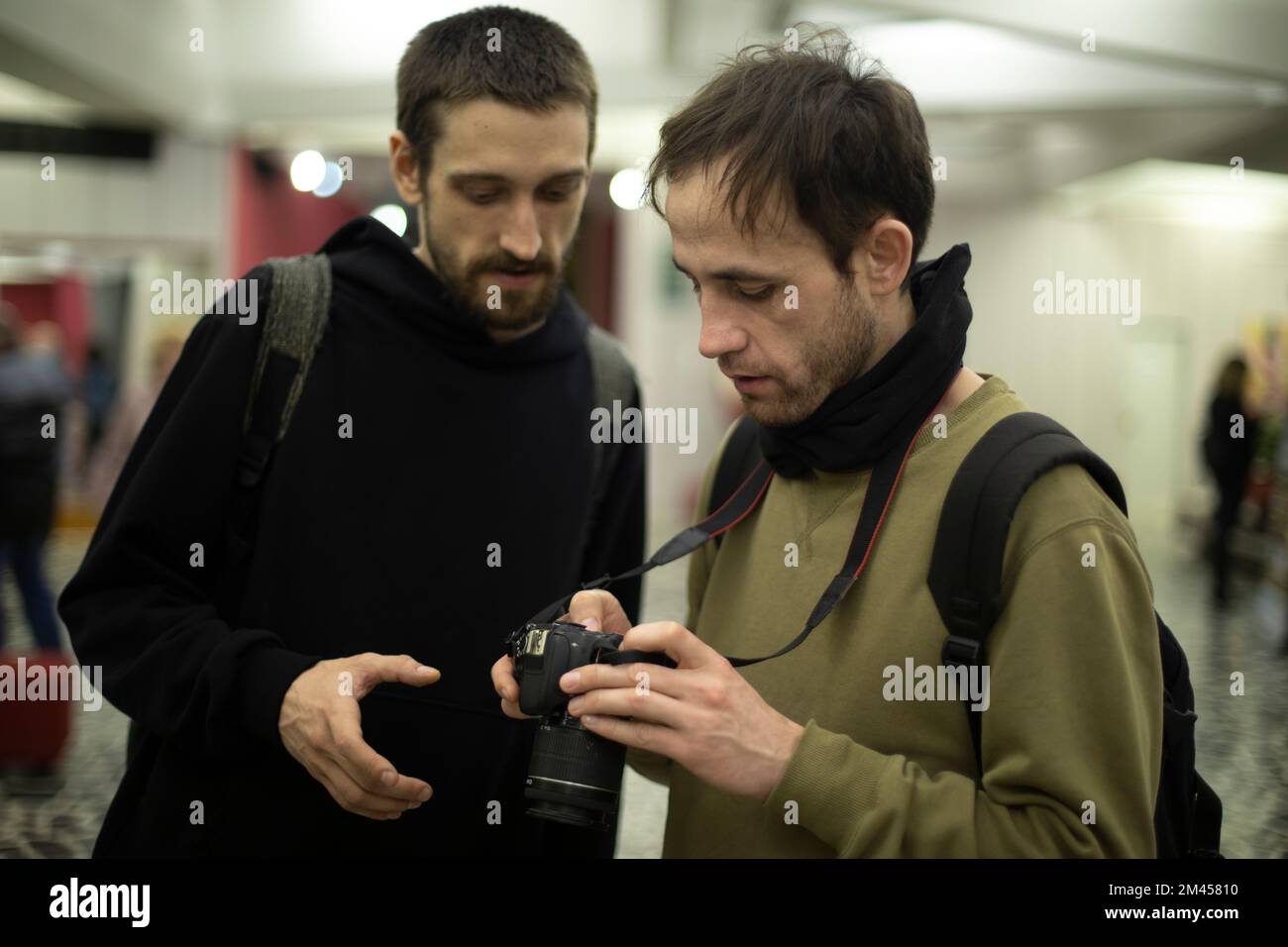 Ragazzi guardano le foto. Gli uomini usano la macchina fotografica. Due studenti imparano a scattare foto. Giovani all'Università. Foto Stock