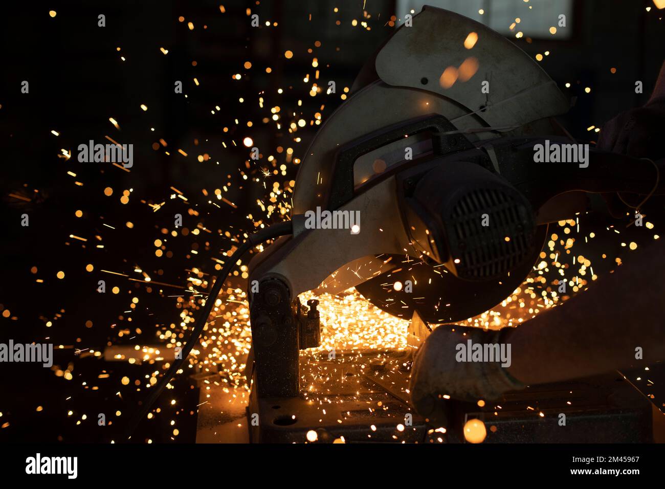 Taglio del metallo con scintille. Luci al buio. Funzionamento dell'attrezzo. La sega grande taglia l'acciaio. Foto Stock