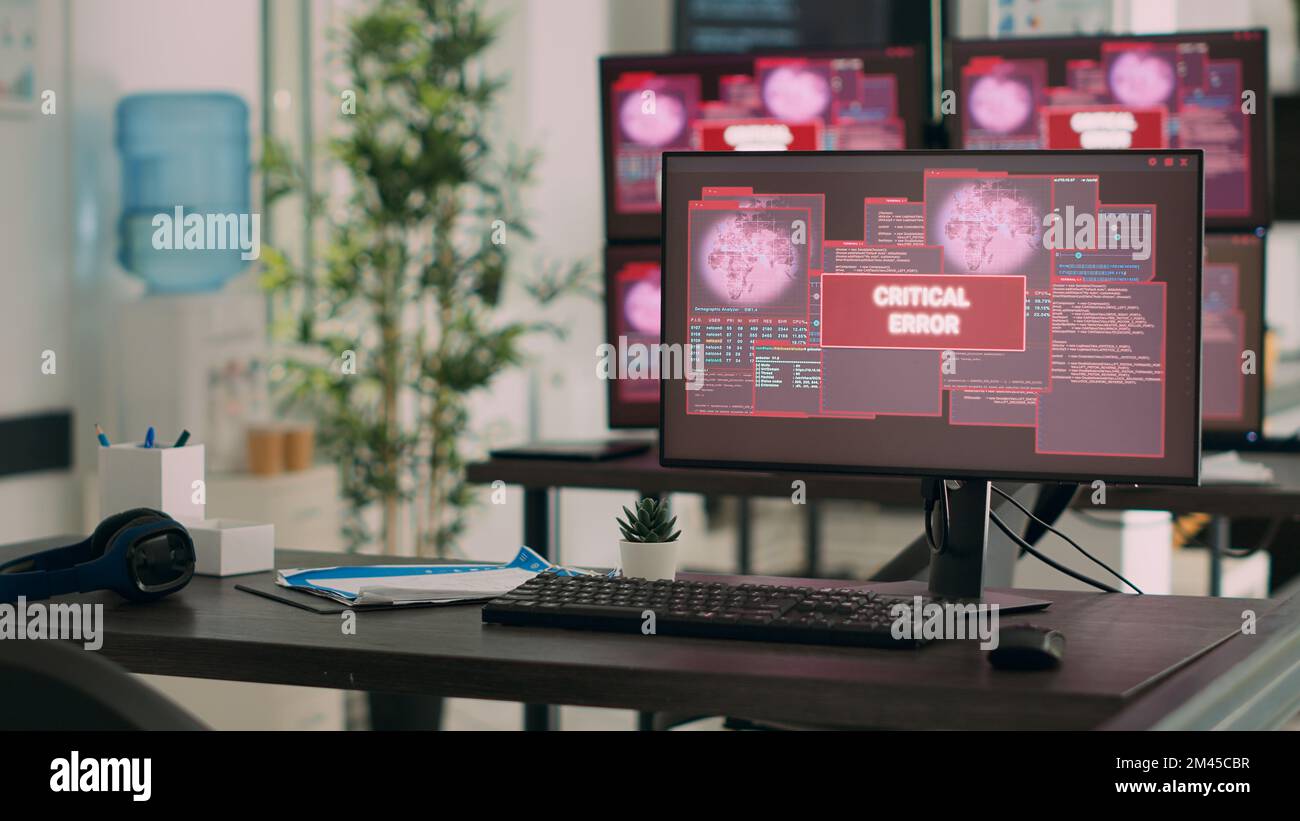 Computer che visualizzano un messaggio di errore critico lampeggiante sullo schermo, che si occupa di minacce di pirateria informatica e malware. Scrivania vuota con più monitor che mostrano un avviso di violazione della sicurezza. Foto Stock