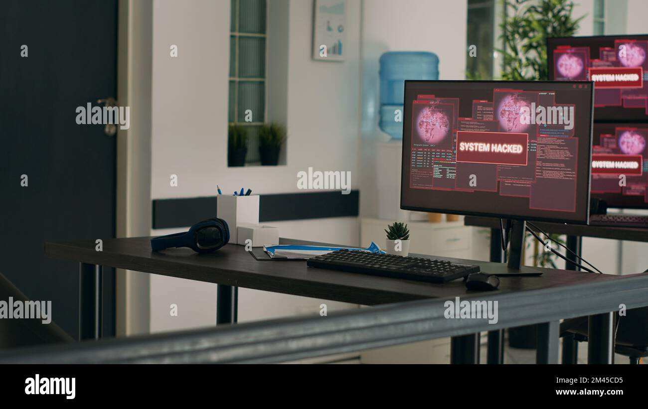 Monitor multipli che visualizzano malfunzionamento del computer e violazione della sicurezza in un ufficio di programmazione vuoto. I computer che visualizzano il messaggio di errore critico lampeggiano sullo schermo e il sistema si blocca sulla scrivania. Foto Stock