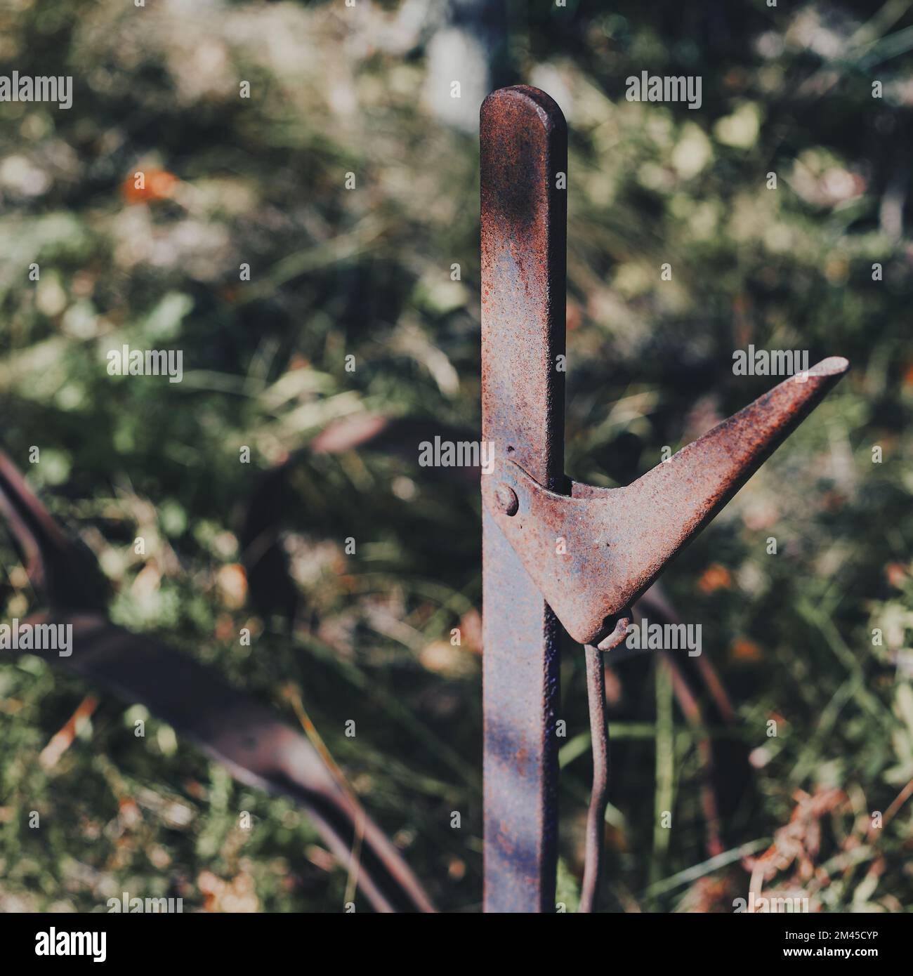 Un'immagine selettiva dell'impugnatura di un vecchio rasaerba a barra falciante arrugginito Foto Stock