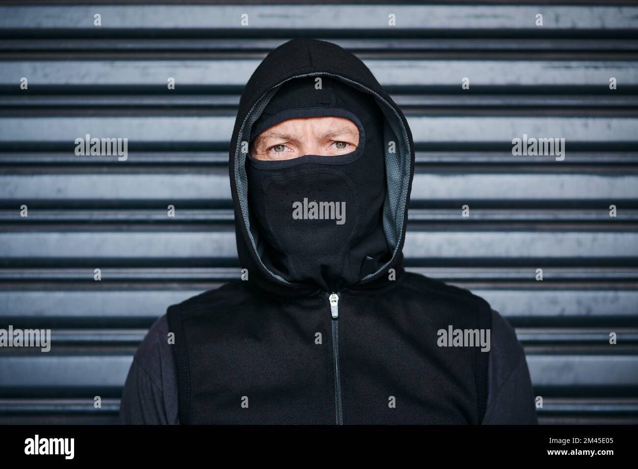 Il volto di un criminale. Ritratto di uno scassinatore maschio che si posa su uno sfondo scuro. Foto Stock