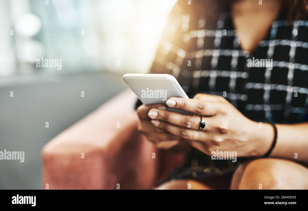 Le donne in viaggio d'affari intelligenti scelgono dispositivi intelligenti. una donna d'affari irriconoscibile che utilizza uno smartphone seduto sul divano di un ufficio moderno. Foto Stock