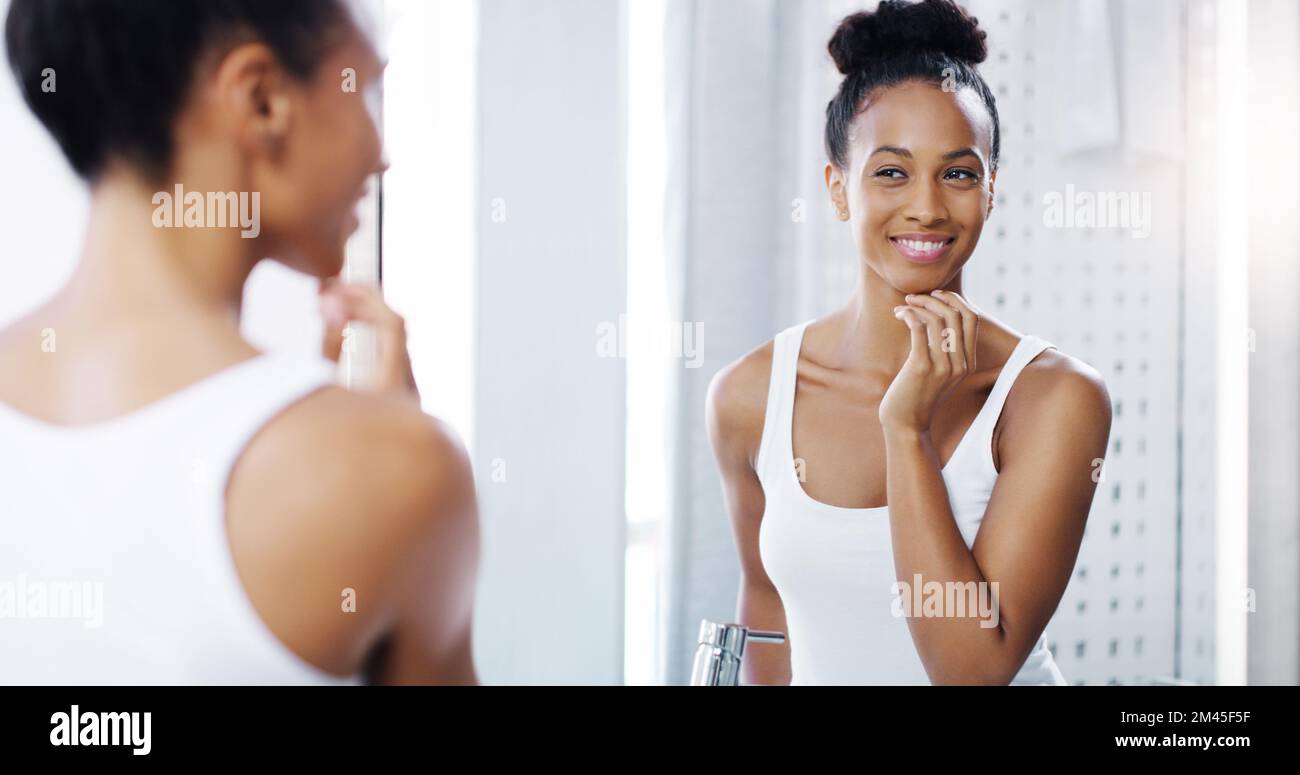 La sua nuova routine di pelle sta già mostrando grandi risultati. una giovane donna attraente ammirando il suo volto nel bagno di casa. Foto Stock