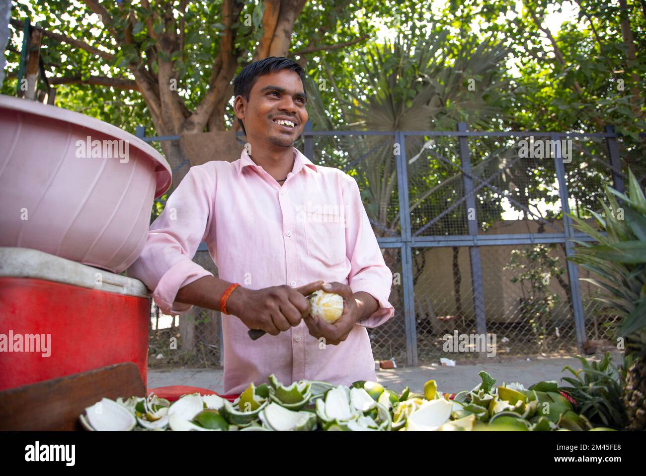 Venditore maschio che sbuccia il lime dolce al suo negozio di succo di strada Foto Stock
