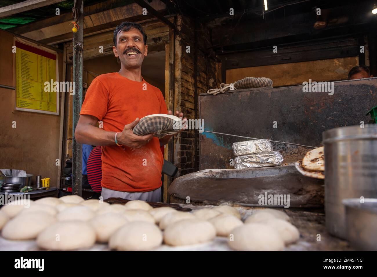 Cuoco di un locale ristorante sulla strada o un dhaba, facendo il pane o un roti, in un forno a legna di argilla o un tandoor Foto Stock